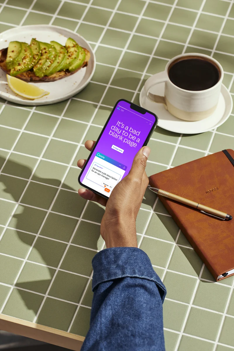 Canva app on a phone held over a café table