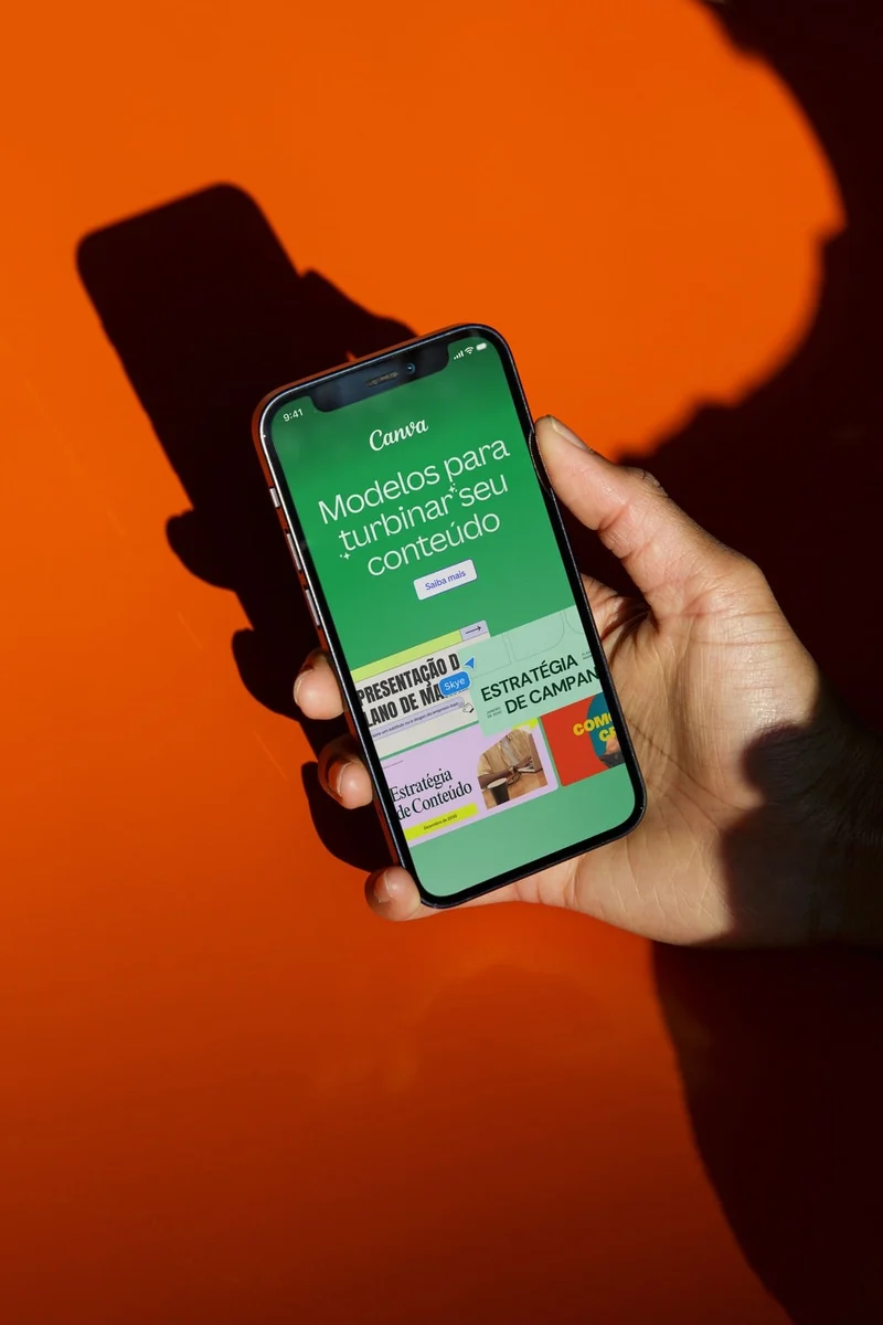 Canva app on a phone held against orange