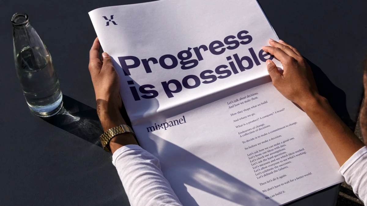Manos con un cartel «Progress is possible» de Mixpanel
