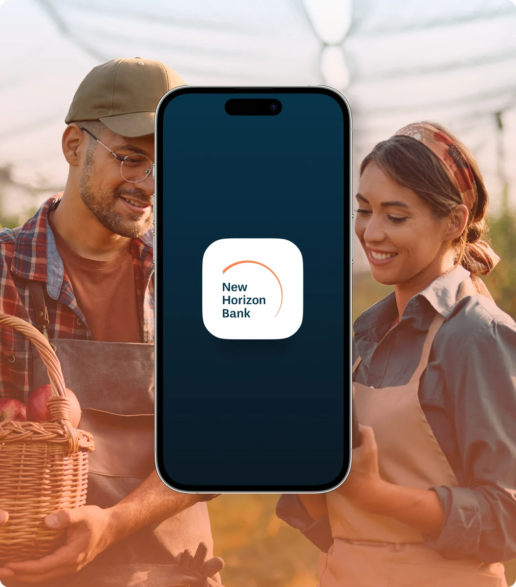 Teléfono con la app de New Horizon Bank sostenido por una pareja en un mercado