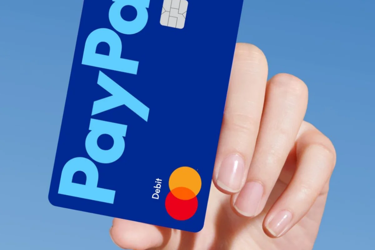 Mano sosteniendo una tarjeta de débito azul de PayPal
