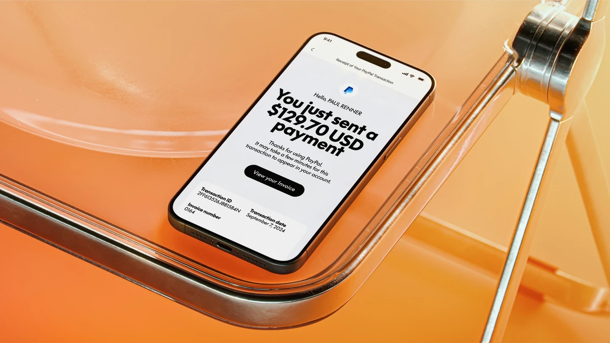 Teléfono que muestra una pantalla de pago de PayPal sobre una superficie naranja