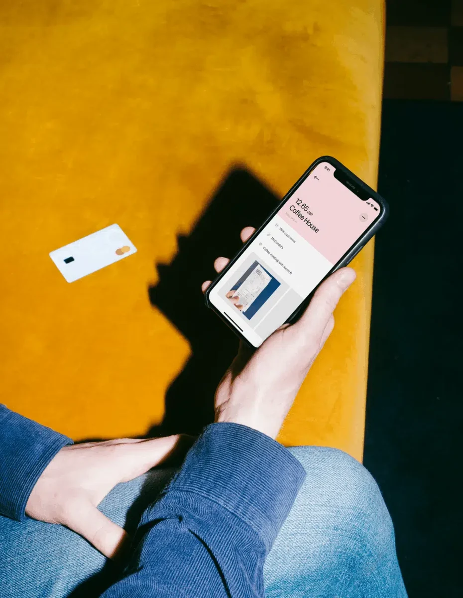 Hand holding a phone with Pleo on yellow