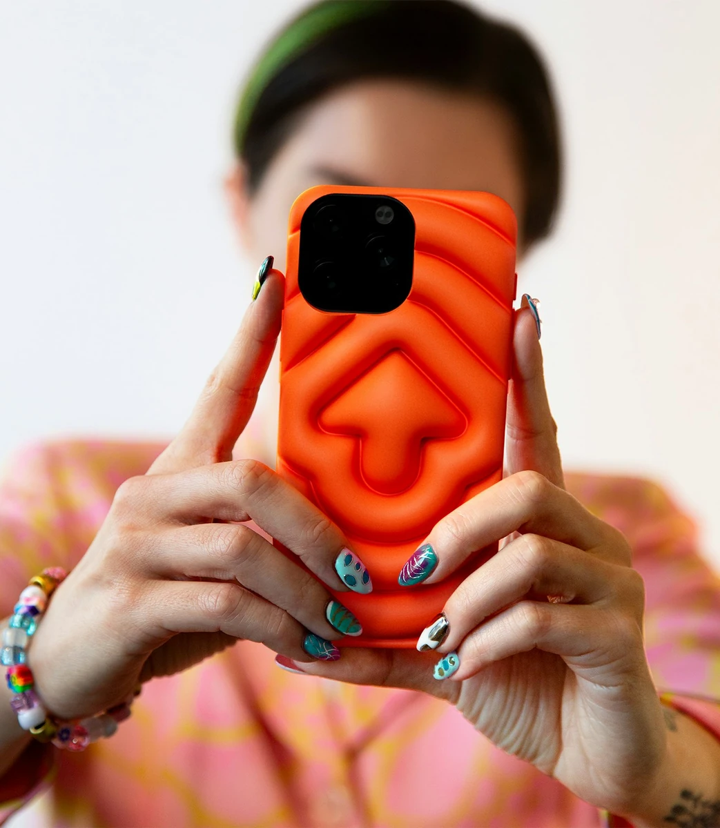 Persona sosteniendo una funda de teléfono naranja con un Snoo esculpido