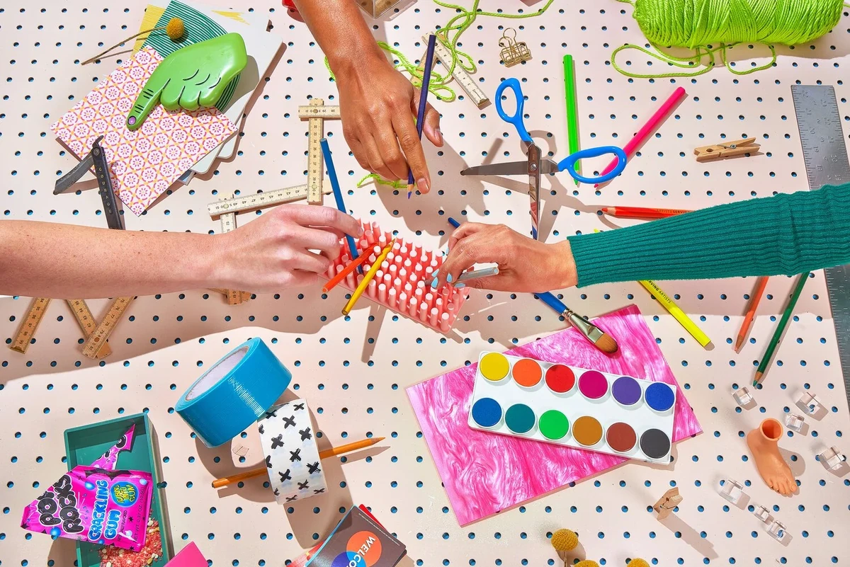 Hands at a table with colourful art supplies