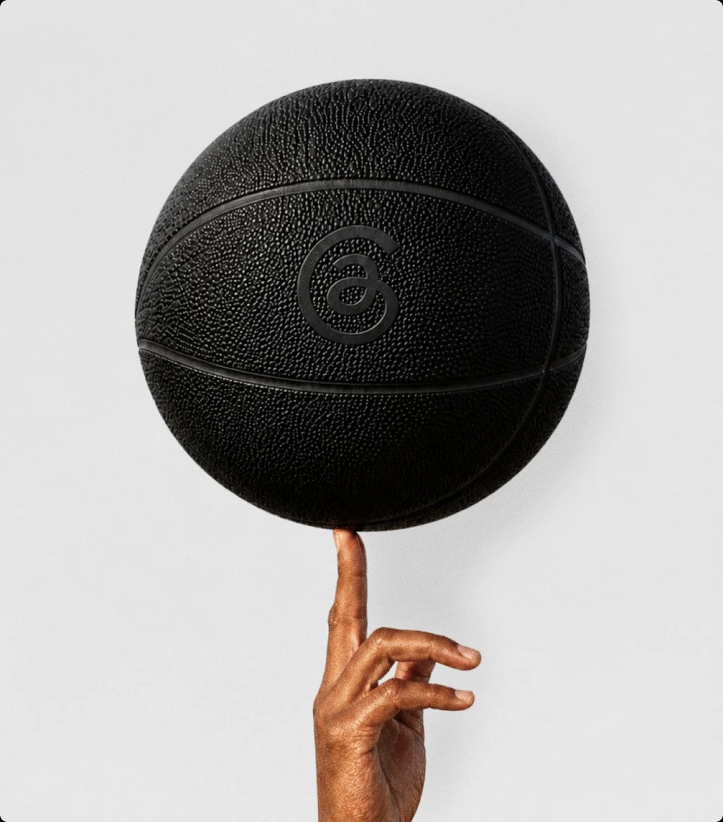 Baloncesto negro con el símbolo @ de Threads grabado, girando sobre un dedo