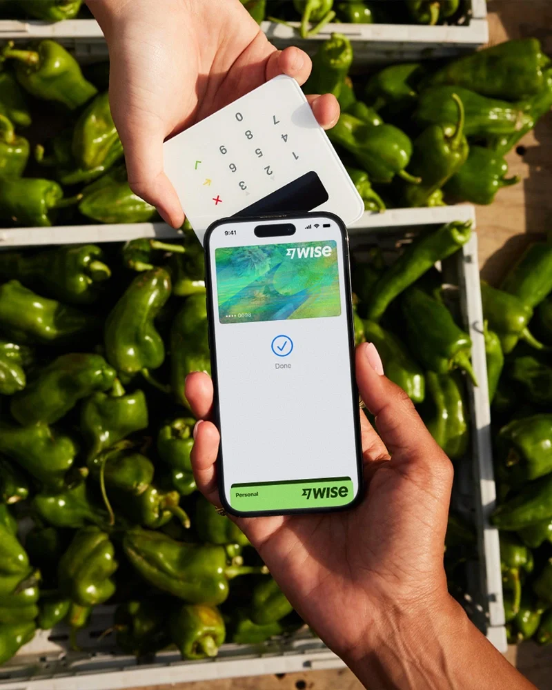 Mano sosteniendo un teléfono con la app de Wise sobre limas