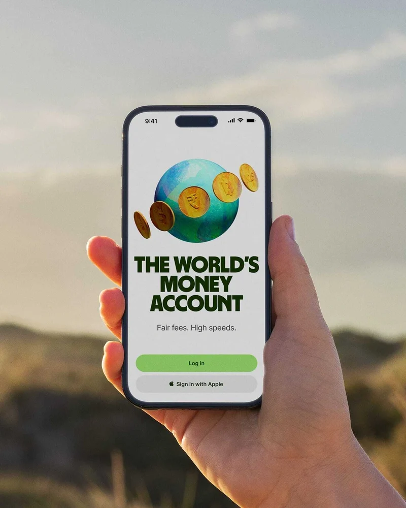 Teléfono mostrando una pantalla de Wise «The world's money account» al atardecer