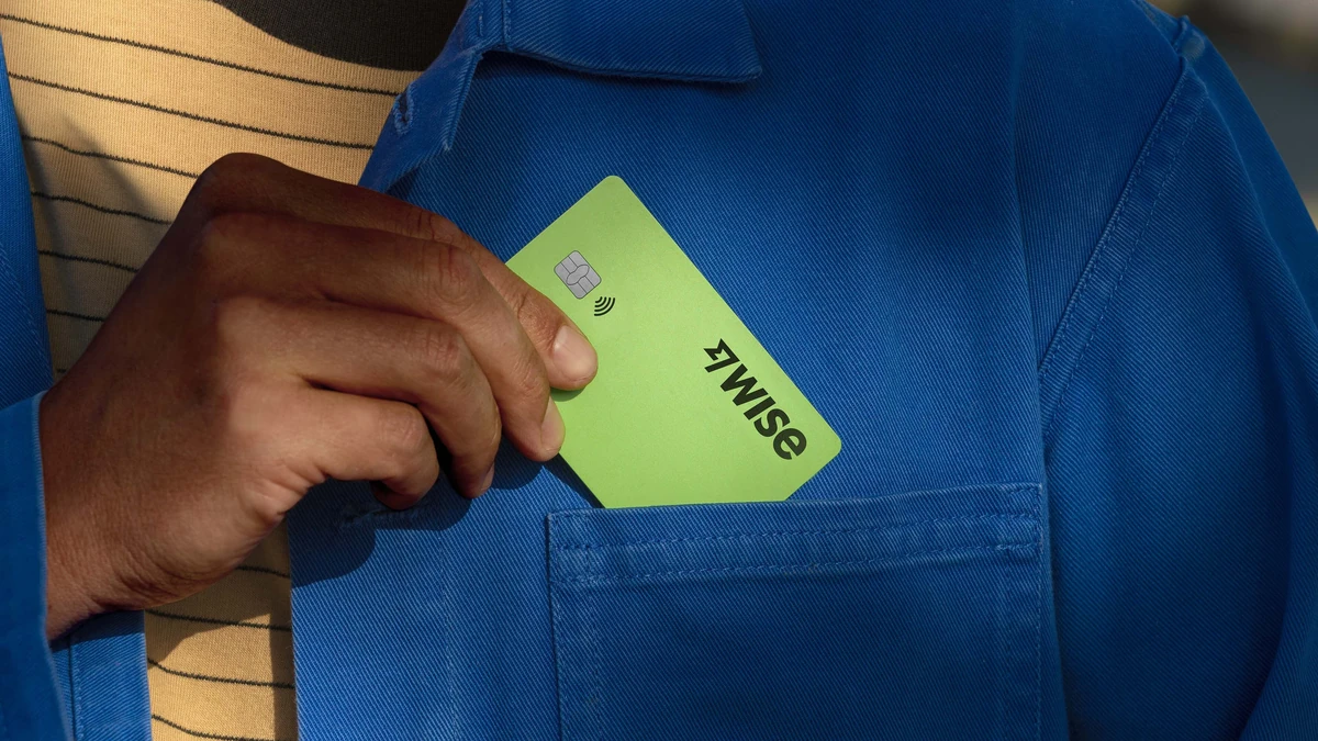 Mano sacando una tarjeta verde de Wise de un bolsillo de chaqueta